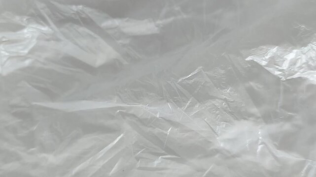 White crumpled plastic film seamless rotating motion background with wrinkled texture.