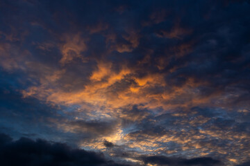 Obraz premium Dramatic golden and dark blue clouds stretching across a twilight sky