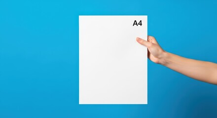Hand holding A4 paper on blue.
