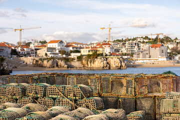Stacked fishing traps with Cascais coastal town background