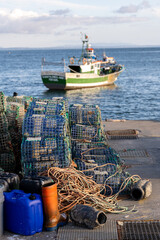 Fishing traps stacked on dock with boat offshore