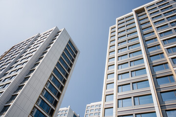 Obraz premium Modern high-rise buildings captured from a low-angle view against a clear blue sky
