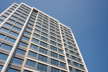 Fototapeta premium Modern high-rise building captured from low angle against clear blue sky