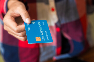 Hand holding a blue credit card ready for payment, symbolizing cashless transactions, banking services, and modern financial lifestyle.