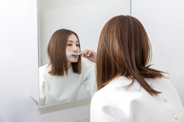 鏡を見て歯磨きする女性