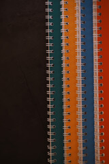 Fototapeta premium Colorful Spiral Notebooks Against Dark Background - Vibrant Stationery Organization Concept
