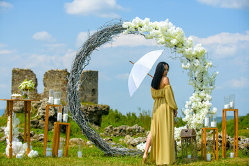 Obraz premium Elegant bride woman under wedding arch. Romantic wedding arch outdoor scene. Bride under floral wedding decor. Luxury wedding arch with flowers. Beauty bride ceremony concept.