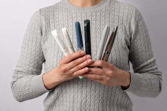 Hands Holding Multiple Insulin and Semaglutide Injection Pens. Close-up of a person holding various medical injector pens for diabetes or weight loss treatment