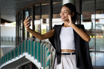 Businesswoman smiles while holding a smartphone and making a video call in the office
