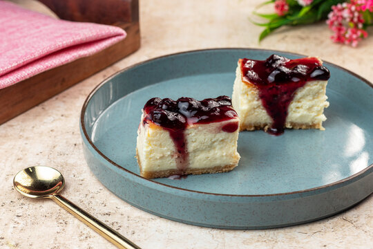 Blueberry Cheesecake is a rich and creamy dessert made with smooth baked cheesecake filling on a buttery biscuit crust, topped with glossy blueberry compote and fresh blueberries. The vibrant purple t