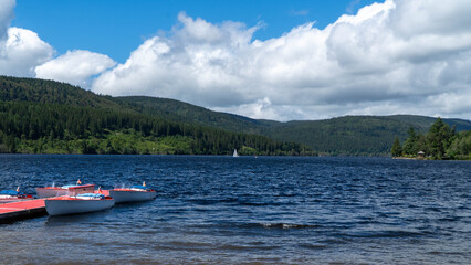 Fototapeta premium A row of colorful pedal boats waiting by the pier on the calm waters of Lake Schluchsee, in southern Germany