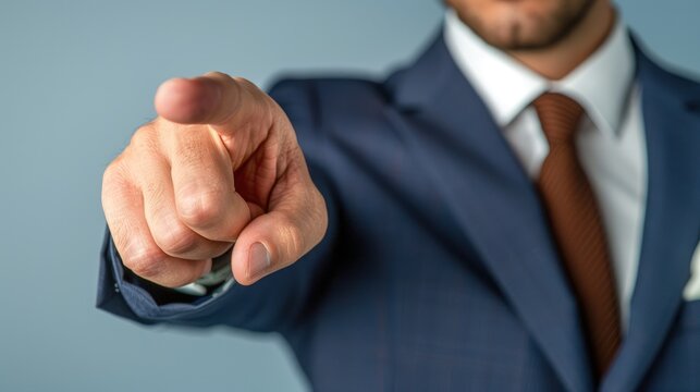 Businessman in suit points index finger forward, directing attention to viewer