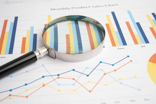 Magnifying glass on charts graphs paper.