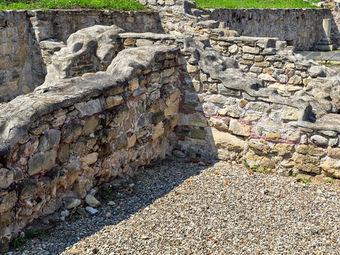 Ruins of the Apulum Roman castrum in Alba Iulia, Romania. Ancient stone walls with concrete and gravel ground at an archeological site on a sunny day.