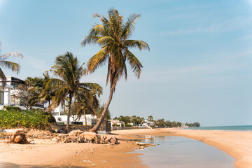 Tropical beach with resort and palm trees on sunny day