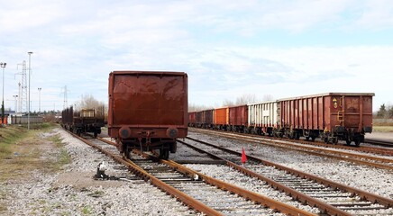 Obraz premium Railway wagons waiting on dead end railroad under a cloudy sky. Rear view.