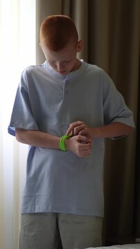 A teenager in a hotel room puts on an RFID or NFC bracelet. A boy puts on a contactless bracelet on his wrist. High quality FullHD footage