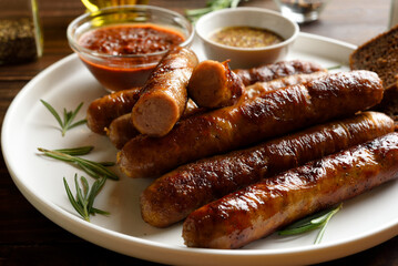 Plate with tasty grilled thin sausages served with sauce
