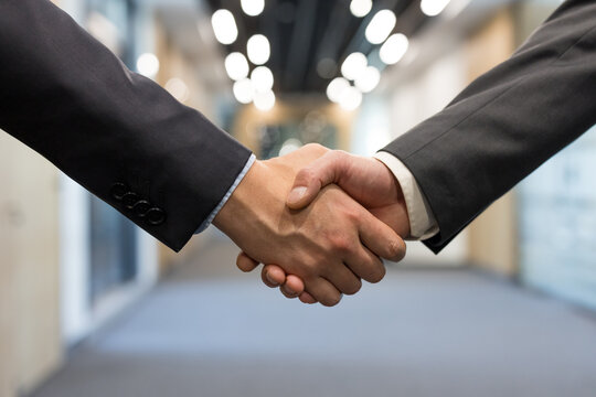 Two business partners shake hands in a close-up office scene, sealing a professional agreement that conveys trust, cooperation, successful partnership and corporate teamwork