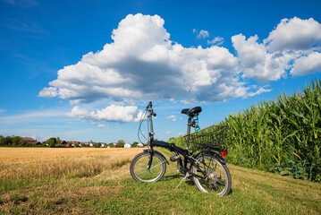 Obraz premium bike on a grassy field lane between grainfield and cornfield, blue sky with clouds