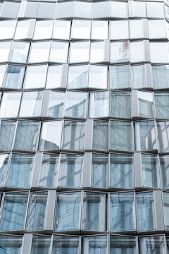 Urban architecture detail of modern glass facade on building with windows reflections and abstract pattern creating contemporary texture background