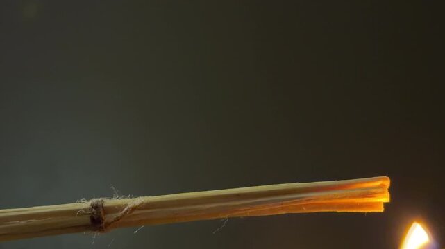 A bundle of thin wooden splinters is lit using a match. The flame spreads across the wood, causing it to catch fire quickly. This ignition creates a distinct and sharp hissing sound
