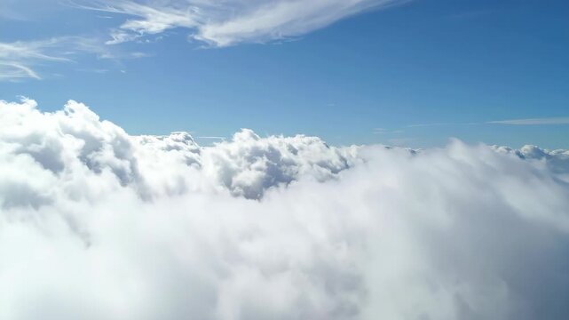Aerial view of fluffy white clouds drifting across a clear blue sky above the stratosphere