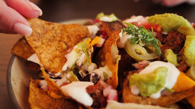 Tasty nachos topped with beef, melted cheese, jalapenos, tomatoes, onions. Perfect for party snack. High quality 4k footage