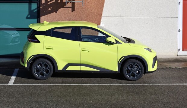 Pasian di Prato, Italy. February 13, 2026. Lime green BYD Dolphin Surf, battery electric compact car, at the roadside. Side view.