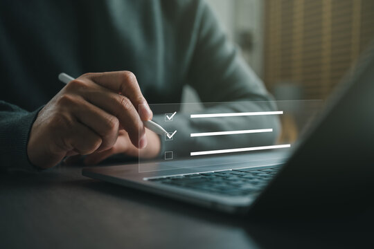 Business professional completing an online checklist on a virtual interface using a stylus and laptop. Concept of task management, digital workflow, productivity, audit, compliance, project planning.