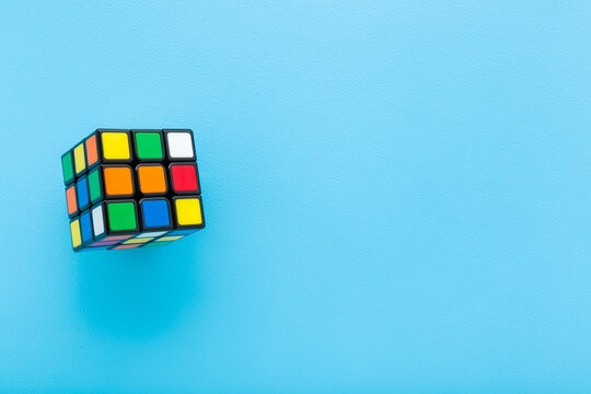 Colorful plastic rubik cube on light blue table background. Pastel color. Closeup. Empty place for text. Top down view.