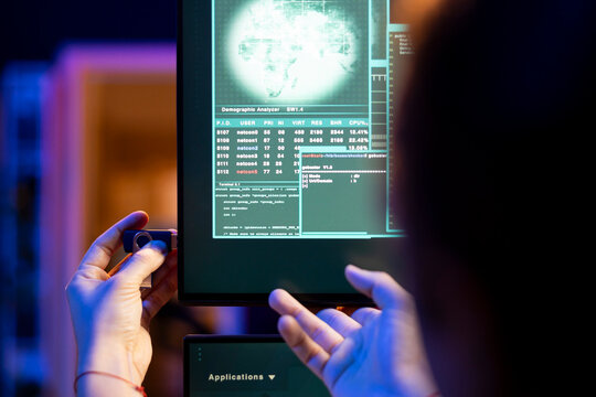 Close up of hacker at home using spyware on USB stick to gather data about user activity. Cybercriminal in neon lit hideout uploading exploits on PC from flash drive to gain unauthorized access