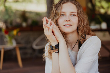 Portrait of a beautiful young woman with long blonde curly hair expressing calm joy.