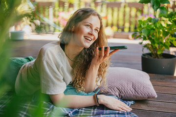 Happy Young Woman Recording Voice Message Outdoors