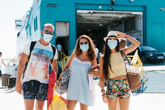Friends wearing masks standing against cruise ship at harbor