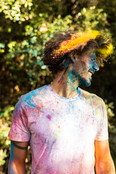 Man shaking his head, full of colorful powder paint, celebrating Holi, Festival of Colors
