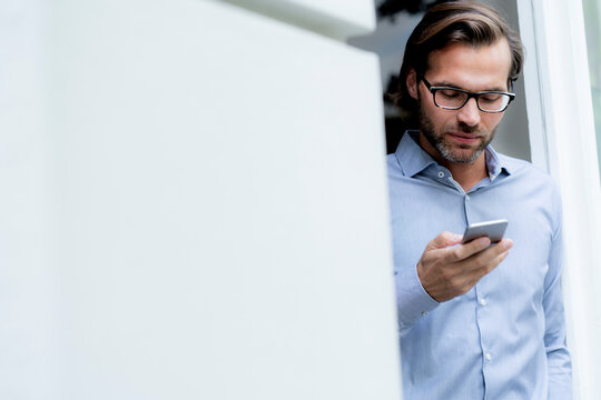 Man standing in doorframe using cell phone