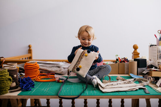 Happy little girl sitting on table with fashion accessories