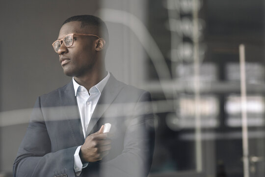 Portrait of young businessman behind diagram on glass pane in office
