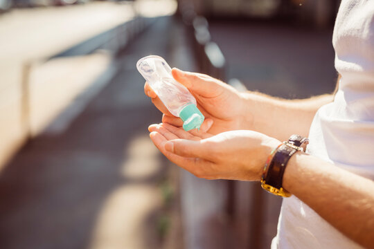 Close-up of young man washing hands with sanitizer while standing outdoors