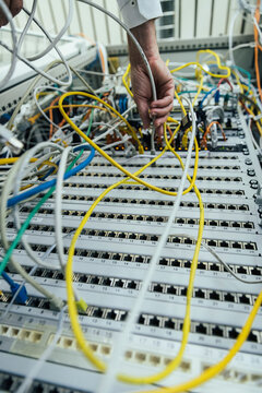Mature man hand plugging in cable on data center rack