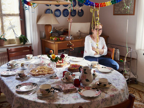 Woman in bad mood waiting at laid table for guests
