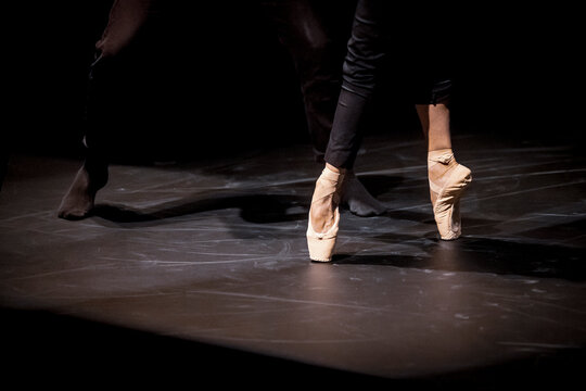 Close up of dancers dancing en pointe on black stage