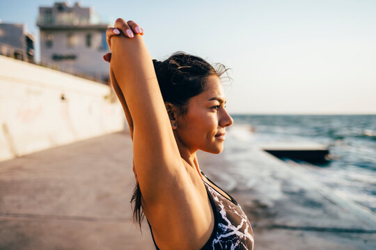 Young sportswoman stretching her arm
