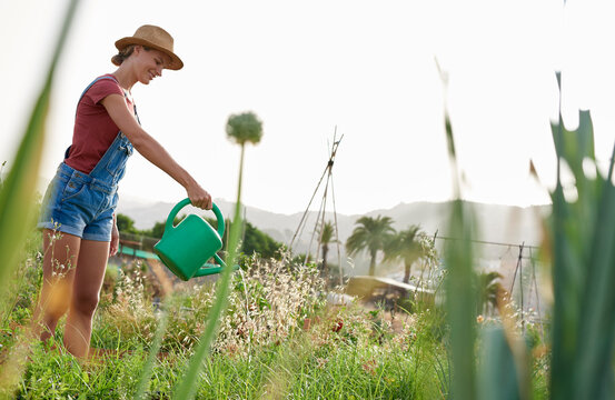Smiling young farmer with watering can