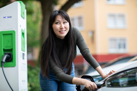 Carsharing, woman charging an electric car