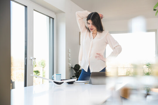 Young woman standing at table at home looking at plane model