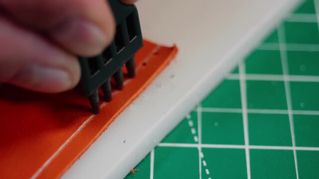 A tanner measures and cuts leather carefully. The process includes using tools to mark and create neat lines on the material. This takes place in a workshop setting where precision is key.