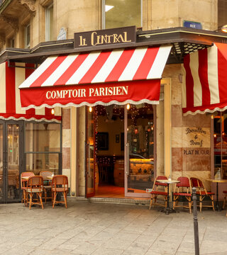 Paris, France - October 13, 2025: Traditional Parisian cafe exterior with red striped awning and outdoor dining tables