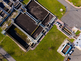 Facilities for wastewater treatment located in a green area with tanks and pipelines during daylight hours